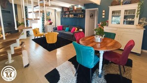 Un soggiorno moderno con una scala, un'area pranzo con sedie colorate e una cucina con armadi.
