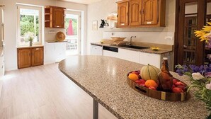 A kitchen with wooden cabinets, a granite countertop, and a fruit bowl.