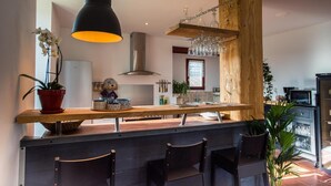 Una cocina moderna con barra de madera, luces colgantes y un botellero.