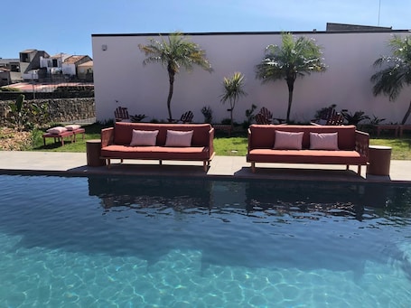 Una piscina al aire libre, sombrillas, sillones reclinables de piscina