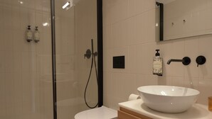 A modern bathroom with a glass-enclosed shower, a white toilet, and a wooden vanity with a white basin. - The Farm - Azores Boutique House (Ponta Delgada)
