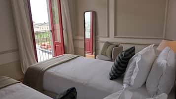 Habitación de hotel con dos camas, un espejo grande y vistas al balcón exterior.