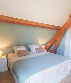 A bedroom with a bed, wooden beams, and a nightstand.