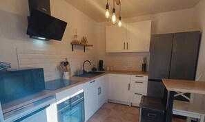 Een moderne keuken met witte kasten, een inbouwoven, een magnetron en een koelkast.
