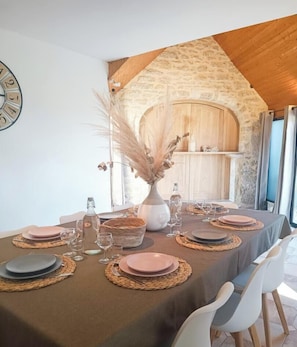 A dining table set with plates, glasses, and a vase with dried plants.