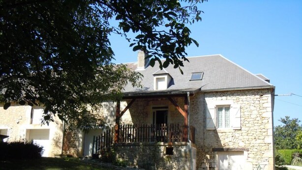 A stone house with a wooden porch, a small window, and a door. - Gîtes de France® - L'Oustal (SAINT-SOZY)