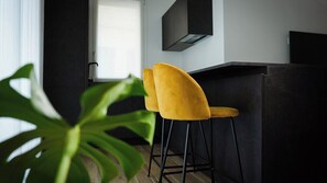 A modern kitchen with two yellow chairs, a black countertop, and a large green plant in the foreground. - Palazzo Gilberto (Padova)