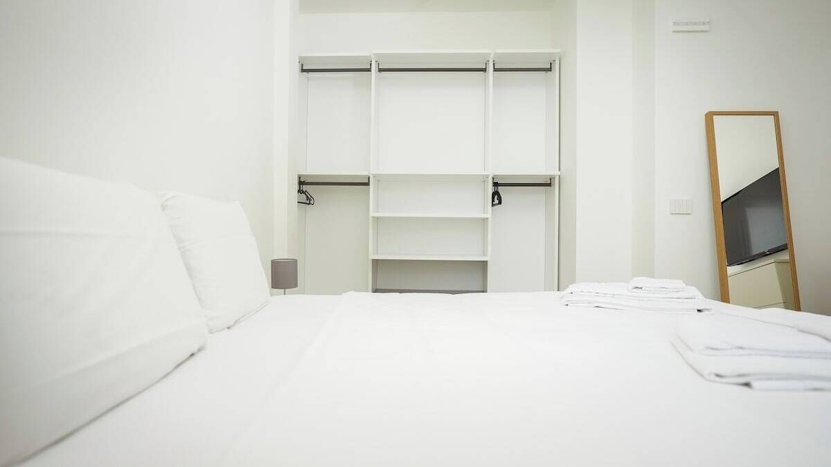 A hotel room with a bed, a white wardrobe, and a mirror.