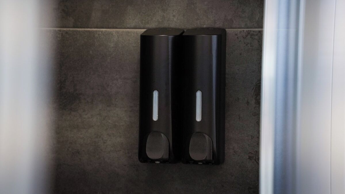 Two black soap dispensers on a tiled floor.
