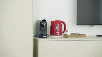 A kitchenette with a coffee maker, a red kettle, a remote control, and a box of tissues on a counter.