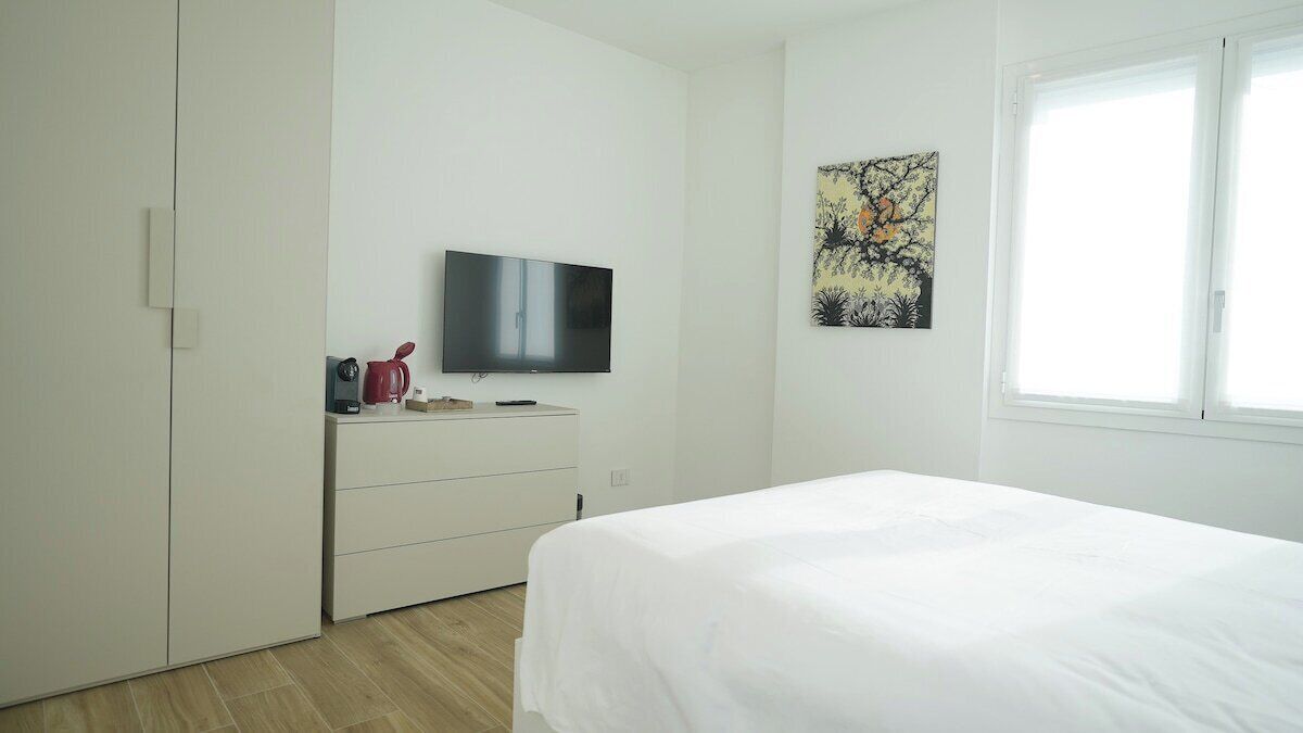 Una camera da letto con un letto, una TV, un comò e una finestra.