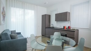 Une cuisine moderne avec un coin repas, un canapé et une table en verre.