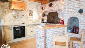 Eine rustikale Küche mit Backsteinwand, Holzschränken und einem eingebauten Backofen.