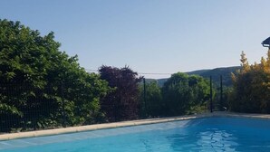 Une piscine d’eau bleue et limpide, entourée de verdure et délimitée par une clôture.