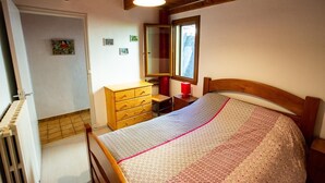 Une chambre à coucher avec un lit en bois, une commode, un miroir et une fenêtre.