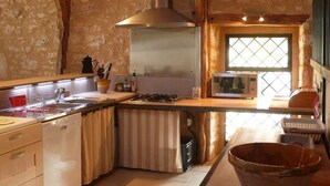 Cocina compacta con estufa a gas, campana extractora de acero inoxidable y ventana con diseño de celosía.