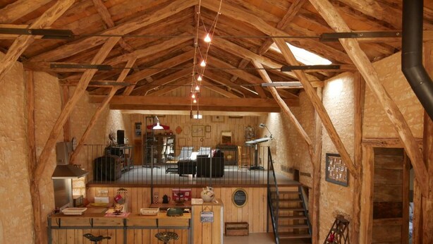 Un interior rústico de madera con cocina, comedor y una escalera que sube a un nivel superior.
