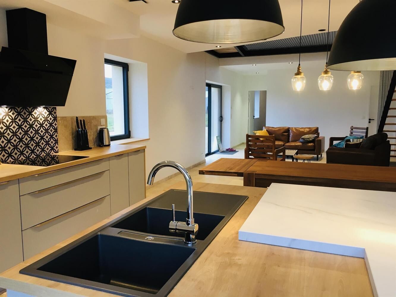 Une cuisine moderne avec un évier noir, un plan de travail en bois et des luminaires suspendus.