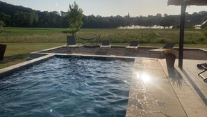 Una piscina con sillones de descanso y vistas a un campo de golf.