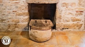 A stone fireplace with a rustic design, a small table with a lamp, and a woven basket.