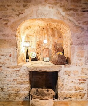 Una chimenea de piedra con diseño rústico, una mesita con lámpara y una cesta tejida.
