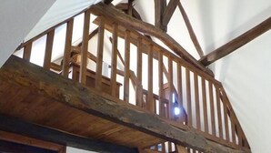 Een kamer met een hemelbed van hout, een ladder, een bureau met een computer en een raam met jaloezieën.