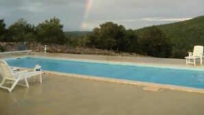 A swimming pool with lounge chairs and a rainbow in the background.