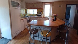 A kitchen with a central island, bar stools, and a window.