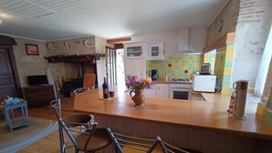 A kitchen with a wooden island, bar stools, a coffee machine, and a tiled backsplash.