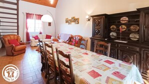 A dining area with a long table, chairs, and a chandelier. - Gîtes de France® - L'Escurol (BRETENOUX)
