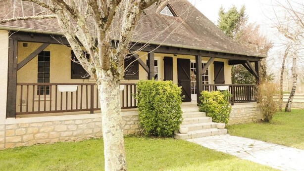 A stone building with a gabled roof, a covered porch, and a staircase leading to the entrance. - Gîtes de France® - L'Escurol (BRETENOUX)