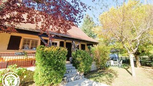 A house with a red roof, a porch, and a stone staircase leading to the entrance. There are potted plants and a fence visible. - Gîtes de France® - L'Escurol (BRETENOUX)