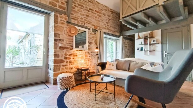 Uma sala de estar aconchegante com parede de pedra, sofá, mesa de centro e uma poltrona.