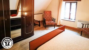 Un dormitorio con cama, una silla, escritorio y armario.