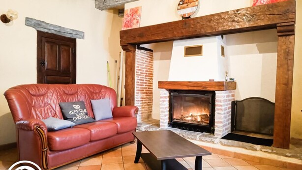 Una sala de estar con un sofá de cuero rojo, una mesa de centro de madera y una chimenea de ladrillo.