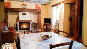 Una sala de estar acogedora con chimenea, televisor y una mesa de comedor para cuatro.