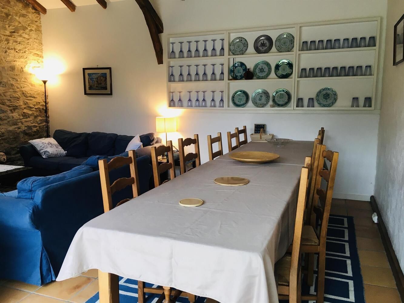 A dining area with a long table, chairs, and a wall-mounted plate rack.