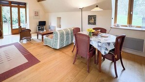 Una sala acogedora con sofá, mesa de comedor, sillas, televisor y chimenea.