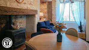 Una habitación rústica con paredes de ladrillo visto, una chimenea, una mesa de comedor y un sofá azul.