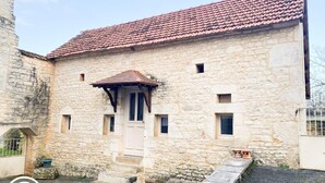 A stone building with a tiled roof, a wooden door, and small windows.