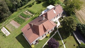 A large two-story building with a red-tiled roof, surrounded by well-maintained gardens and fields. - Gîtes de France® - La Cigale (SAINT PROJET)