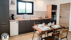 Eine moderne Küche mit Essbereich, mit einem Holztisch für zwei Personen, einem eingebauten Backofen und einem Fenster mit Blick.