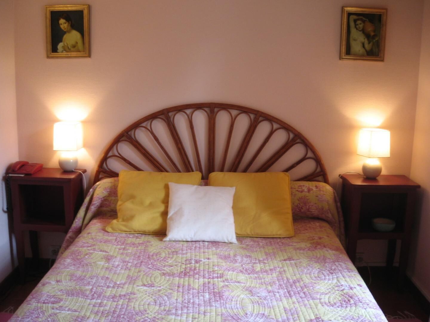 A bed with a unique headboard, two bedside lamps, and a floral-patterned bedspread.