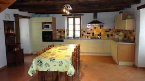 A kitchen with a dining table, cabinets, and a tiled backsplash.