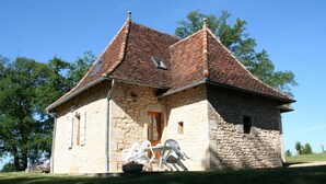 A stone building with a pitched roof, a wooden door, and two windows.