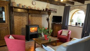 A cozy living room with a brick fireplace, a television, and comfortable seating.