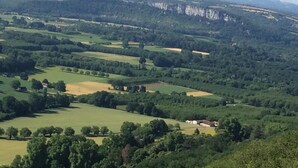 A panoramic view of a rural landscape with rolling hills, scattered trees, and a few buildings. - Gîtes de France® - LE MOULIN (CREYSSE)