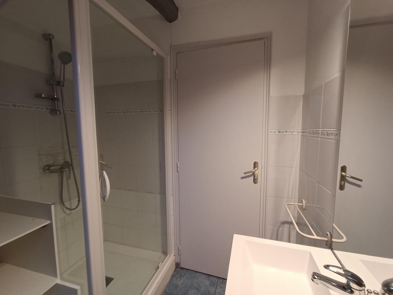 Et badeværelse med bruser, vask og toilet.