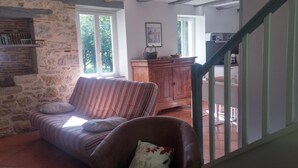 A cozy living room with a striped sofa, a wooden cabinet, and a staircase leading to an upper level. - Gîtes de France® - LE MOULIN (CREYSSE)