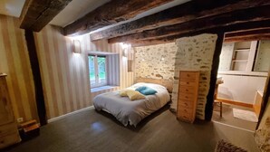 A bedroom with a bed, a dresser, a window, and a view of the outdoors. - Gîtes de France® - Gîte de Larigaldie (SAINT CIRGUES)